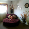 Bed room loft space with 5 foot circular couch (can be custom made) brown crushed velvet with wrinkle fold pattern, antique overhead lighting with black vase and colorful  side dryed flowers. 